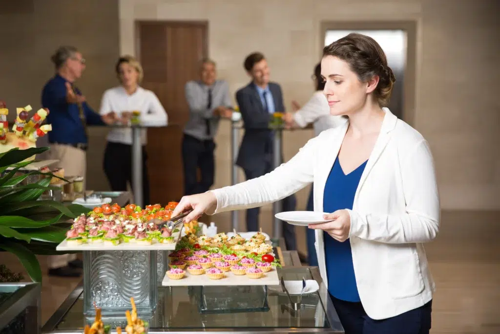 Buffet traiteur en entreprise avec une femme se servant en amuse-bouches lors d’un événement professionnel