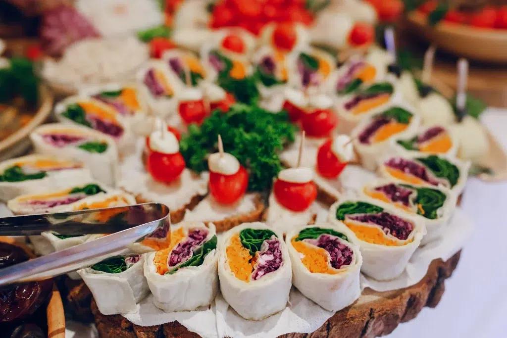 Assortiment coloré de wraps végétariens et bouchées apéritives sur un plateau traiteur.
